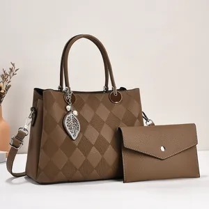 Detail of brown litchi pattern leather tote bag set with metal leaf charm and bead