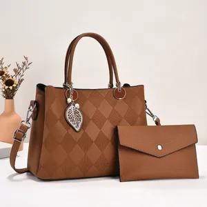 Detailed view of caramel brown tote bag with quilted pattern and metal leaf charm