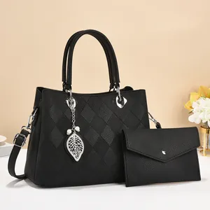Detail of black pebbled leather tote bag with quilted pattern and leaf charm