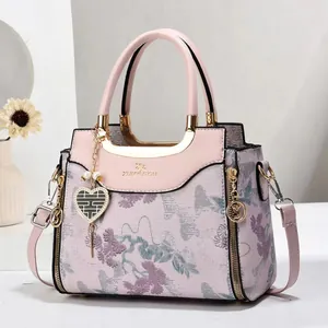 Pink structured handbag with floral embroidery and gold accents shown with accessories