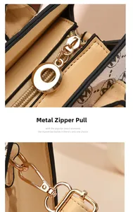 Macro shot of golden metal zipper pull and lobster clasp hardware on a monogram handbag