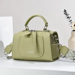 Detail view of green pebble leather Boston bag with stylish geometric woven strap