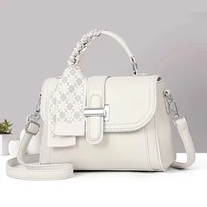 Detail of off-white lychee leather handbag with woven handle and plaid silk scarf decoration