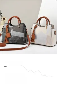 Detail of color-blocked leather handbags in grey and beige with decorative tassels