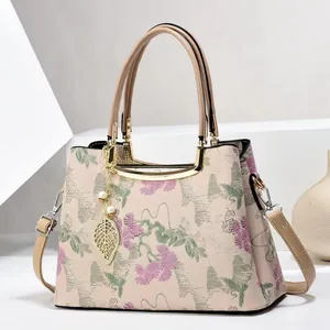 Detail of embroidered floral jacquard handbag with leaf pendant and pearl decoration