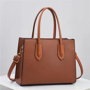 Brown Saffiano leather tote bag with gold hardware on white marble surface