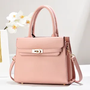 Detail of pink lychee leather handbag with golden twist lock and orchid decoration