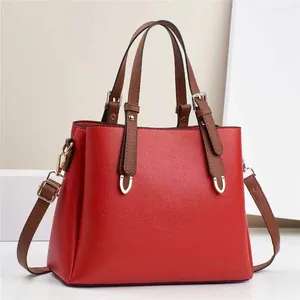 Detailed close-up of red lychee pattern leather handbag with brown handles and gold hardware
