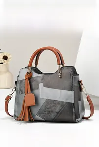 Detail view of stylish patchwork handbag with grey and brown leather panels and tassel