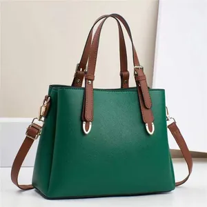 Detail view of dark green pebbled leather texture and gold hardware on the handbag