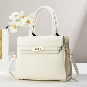 Detailed view of white lychee leather texture and golden metal twist lock on tote bag
