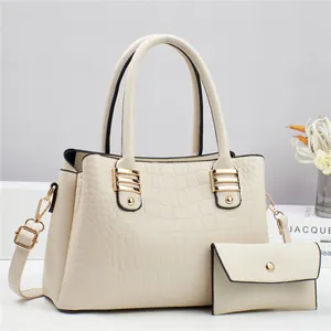 Close-up of cream crocodile-embossed handbag set with elegant golden hardware details