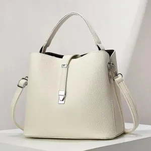 Detail of cream pebbled leather bucket bag with silver metal lock and top handle