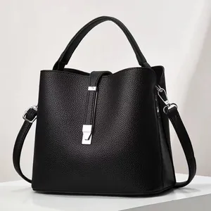 Macro detail of black litchi texture leather bucket bag with silver metal buckle lock