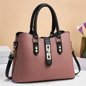 Detail view of pink lychee leather handbag with black handles and golden metal buckle