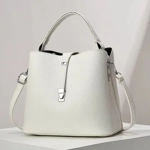 Detail of white lychee pattern leather bucket bag with silver hardware on display stand