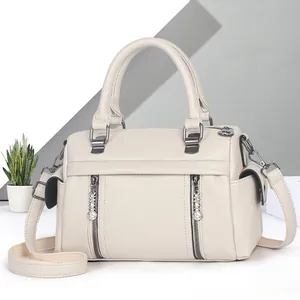 Détails du cuir grainé crème et des fermetures éclair en métal foncé sur le sac à main