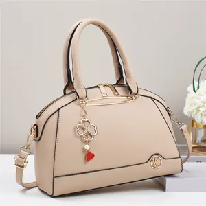 Dettaglio borsa beige con texture grana litchi e ciondolo a cuore quadrifoglio