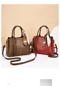 Detail of elegant patchwork leather handbags in brown and red with decorative scarves