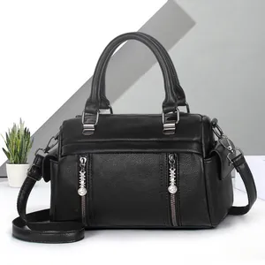 Détail de la texture grainée noire et des finitions gravées sur un sac à main en cuir