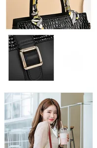 Detail of black crocodile pattern saddle bag with gold buckle and scarf-wrapped handle