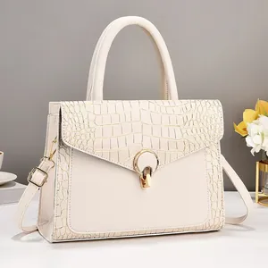 Detail view of beige crocodile embossed leather bag with elegant golden ring lock