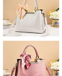 Dettaglio della trama a coccodrillo bianco e rosa con eleganti foulard decorativi sulle borse