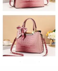 Dettaglio borsa a secchiello rosa coccodrillo con manico dorato e foulard in seta chic