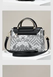 Detail of embroidered wave patterns and golden ring handles on a bicolor handbag