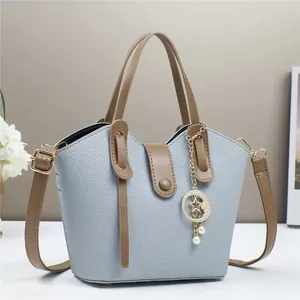 Dettaglio borsa a secchiello blu-grigio con trama a grana e pendente a stella di perla