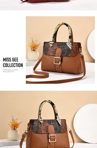 Detail of caramel PU leather handbag with crocodile pattern flap and silk scarf handle