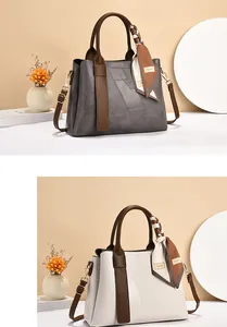 Close-up of elegant patchwork PU leather handbag with silk scarf and gold hardware