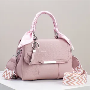 Detailansicht einer rosa Handtasche mit Sternanhänger und gemustertem breitem Gurt