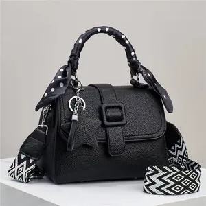 Dettaglio della borsa a tracolla in pelle nera con foulard a pois e ciondolo a stella