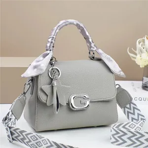 Detail of grey litchi leather handbag with G buckle, silk scarf, and star charm