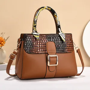 Brown faux leather handbag with crocodile pattern, gold buckle, and decorative scarf