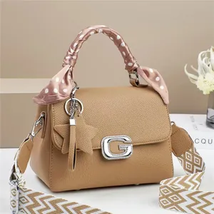 Brown litchi leather handbag with G buckle and pink silk scarf on a book background