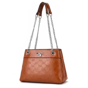 Caramel brown chain shoulder bag with embossed bow patterns and silver metal clasp