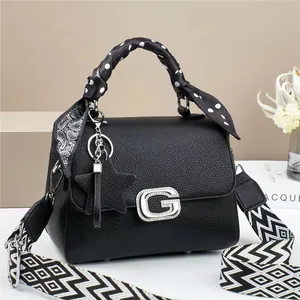 Detail of black lychee leather bag featuring a silver G-buckle and polka dot silk scarf