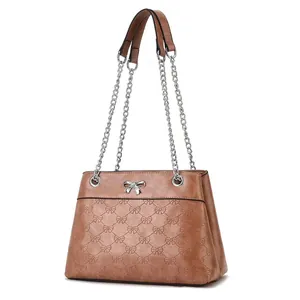 Detail of tan PU leather handbag featuring embossed bows and a silver bow buckle clasp