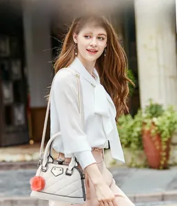 Détail du sac à main brodé blanc avec un charm floral décoratif et des poignées hautes
