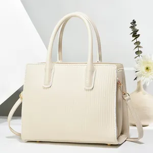 Cream striped embossed tote bag with dual handles and gold hardware in minimalist setting