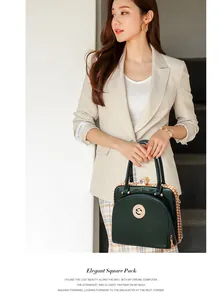 Detail der eleganten dunkelgrünen Lackledertasche mit Goldlogo und Kettenhandgriff