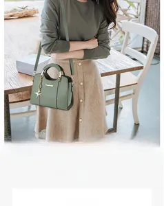 Détail du sac à bandoulière vert sauge avec pendentif étoile et logo métallique chic
