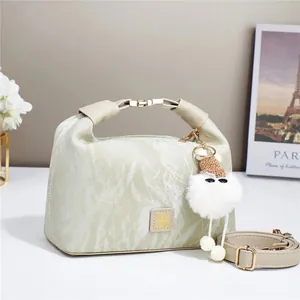 Detail of sage green handbag with marble texture, gold buckle, and plush charm