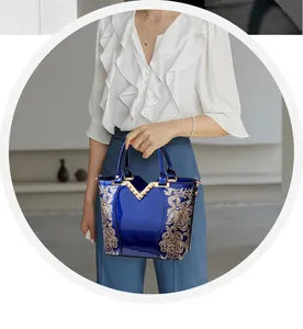 Close-up of elegant royal blue patent leather handbag with floral embroidery and V-metal trim