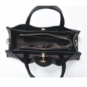 Detail view of the black woven handbag interior with compartments and golden hardware