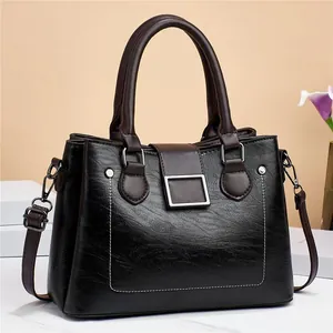 Close-up of contrast stitching and lychee grain texture on dark leather shoulder bag