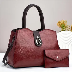 Vue détaillée du sac en cuir brillant bordeaux avec boucle en métal et pochette assortie
