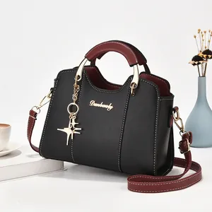 Sac à bandoulière chic noir et bordeaux avec pendentif étoile sous un angle de 45°